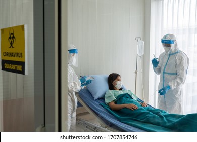 Doctor And Nurse In Personal Pretective Equipment Or Ppe Treating The Asian Woman Patient With Covid-19 Or Coronavirus Infection In The Isolation Unit In The Hospital During Pandemic. Medical Concept