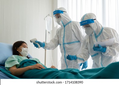 Doctor And Nurse In Personal Pretective Equipment Or Ppe Treating The Asian Woman Patient With Covid-19 Or Coronavirus Infection In The Isolation Unit In The Hospital During Pandemic. Medical Concept