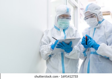 Doctor And Nurse In Personal Protective Equipment Or Ppe Including White Suit, Mask, Face Shield And Gloves Are Discussing About Treatment Of Patient With Coronavirus. Covid-19, Isolation Unit Concept