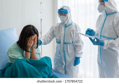 Doctor And Nurse In Personal Protective Equipment Or Ppe Breaking Bad News To Woman Patient That Has Positive Result For Covid-19 Or Coronavirus Infection In Isolation Unit. Medical Concept