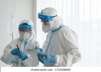 Doctor And Nurse In Personal Protective Equipment Or Ppe Showing Blood Test Tube Of Patient Who Has Covid-19 Or Coronavirus Infection In Hospital. Medical Concept