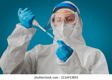 A Doctor Or Nurse In PPE With A Protective Mask, N95 Respirator And Blue Gloves Takes A Sample Used A Dispenser Or Pipette And Test Tube. Research During The Global Covid-19 Pandemic. Selective Focus.