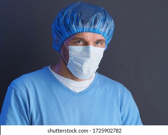 The Doctor Or Nurse Protection Against Coronavirus (COVID-19). Portrait Photo. Male Medical Worker Wearing Protective Face Mask, Head Cover.
