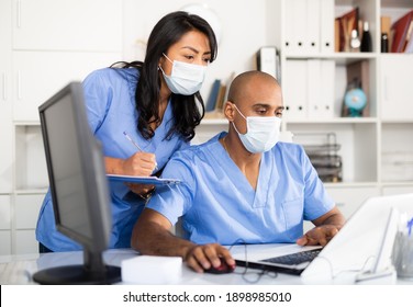 Doctor And Nurse In Protective Medical Mask Check Patient Data In Hospital Computer Database