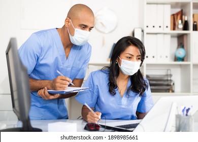 Arzt und Krankenschwester in der medizinischen Schutzmaske überprüfen Patientendaten in der Krankenhausrechnerdatenbank