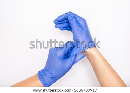 Doctor or nurse putting on blue nitrile surgical gloves, professional medical safety and hygiene for surgery and medical exam on white background.