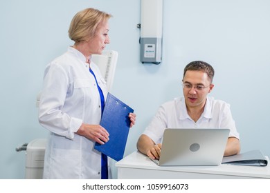 Doctor And Nurse Reviewing Patient Information On A Laptop Computer In An Office Setting