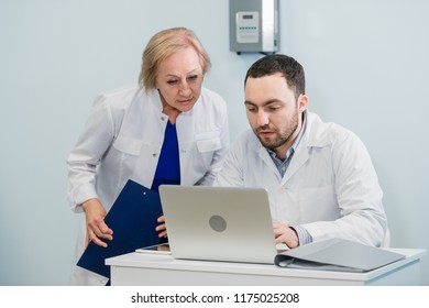 Doctor And Nurse Reviewing Patient Information On A Laptop Computer In An Office Setting