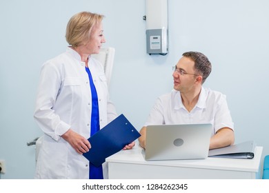 Doctor And Nurse Reviewing Patient Information On A Laptop Computer In An Office Setting