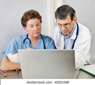 Doctor And Nurse Reviewing Patient Information On A Laptop Computer In An Office Setting