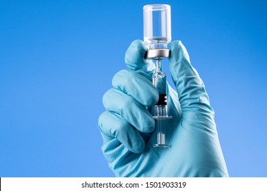 Doctor, Nurse Or Scientist Hand In Blue Glove Holding Flu, Measles, Rubella Or Hpv Vaccine And Syringe With Needle Vaccination For Baby, Child, Woman Or Man Shot, Medicine Vial Dose Injection