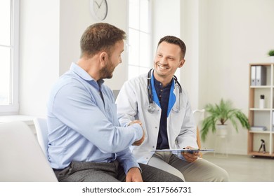 Doctor or nurse shakes hands with a male patient during visit to the hospital clinic. The handshake symbolizes professional medical care, trust, and the importance of patients healthcare. - Powered by Shutterstock