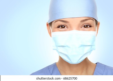 Doctor / Nurse Smiling Behind Surgeon Mask. Closeup Portrait Of Young Asian Caucasian Woman Model In Blue Medical Scrub.