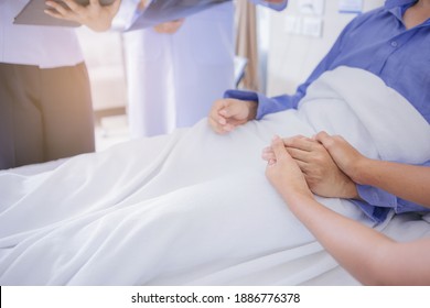 Doctor And Nurse Talk With Husband Patient About Examining Result From Doctor, Family Health Care, Palliative Care, With Wife Holding Hand Of Patient At Hospital