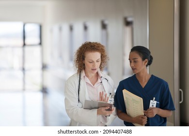 Doctor And Nurse Talking In Hospital Hallway