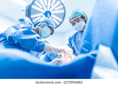 Doctor and nurse team in blue uniform did surgery inside operating room in hospital.Asian surgeon did orthopedic or cosmetic surgery.Surgical treatment in theater.Medical device used in hospital.