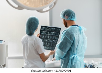 Doctor and nurse in uniform look and discuss an X-ray or MRI scan of the patient spine - Powered by Shutterstock