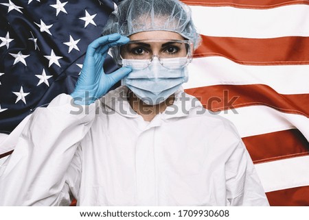 Doctor or Nurse Wearing Medical Personal Protective Equipment (PPE) Against The American Flag Banner.
