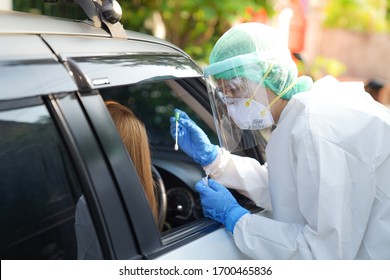 Doctor or nurse wearing PPE, N95 mask, face shield  and personal protective gown standing beside the car/road screening for Covid-19 virus, Nasal swab Test. 
