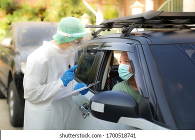 Doctor Or Nurse Wearing PPE, N95 Mask, Face Shield  And Personal Protective Gown Standing Beside The Car/road Screening For Covid-19 Virus 