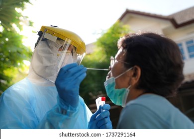 Doctor Or Nurse Wearing PPE, N95 Mask, Face Shield  And Personal Protective Gown Screening For Covid-19 Virus, Nasal Swab Test. 