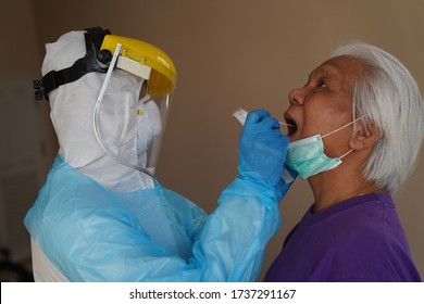 Doctor Or Nurse Wearing PPE, N95 Mask, Face Shield  And Personal Protective Gown Screening For Covid-19 Virus, Throat Swab Test. 