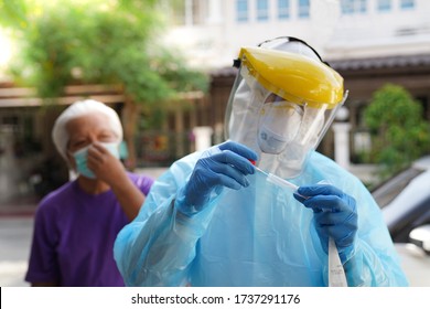 Doctor Or Nurse Wearing PPE, N95 Mask, Face Shield  And Personal Protective Gown Screening For Covid-19 Virus, Nasal Swab Test. 