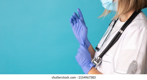 Doctor or nurse in white medical suit puts on protective gloves. Close-up. Concept of professional clinical care, uniform and healthcare.