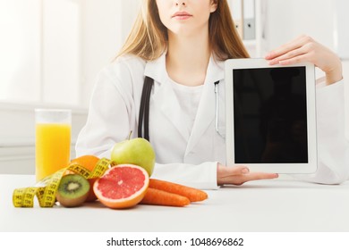 Doctor Nutritionist With Fruits And Holding Blank Digital Tablet, Healthy Eating And Slimming Concept. Mockup For Right Nutrition Menu, Copy Space