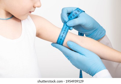 Doctor Nutritionist Measures The Thickness Of The Child's Hand With A Measuring Tape. The Concept Of Being Too Thin, Underweight, Close-up.