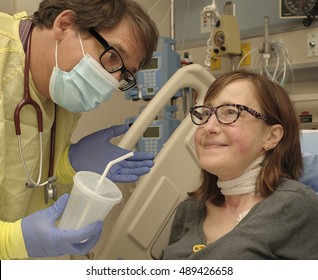 Doctor Offers Water To A Female Patient Recovering After Surgery In Post Operative Care Room In Modern Hospital.