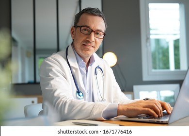 Doctor in office working on laptop 