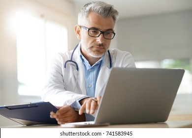 Doctor In Office Working On Patient File