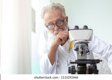 Doctor older or seriously scientist working with a microscope in Laboratory.