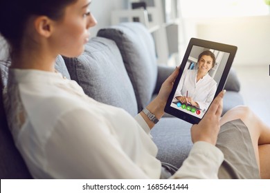 Doctor Online. The Doctor Conducts A Consultation Advises A Young Woman Patient Using A Gadget In Room House.