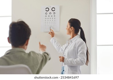 Doctor ophthalmologist or optometrist, conducts a vision checkup for a patient using a vision chart in a clinic. Healthcare professional provides ophthalmology care to ensure the patient eye health. - Powered by Shutterstock