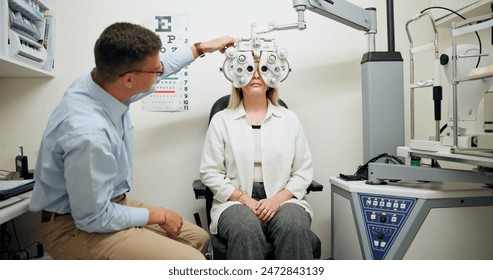 Doctor, ophthalmologist and woman on phoropter for eye care, consultation or health exam in clinic. Optometry, test or patient on lens machine tools for vision check, wellness and eyesight correction - Powered by Shutterstock