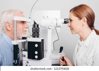 Doctor Optometrist Examining Old Man's Eyes With Special Eye Equipment