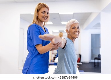 Doctor orthopedic teaching senior woman to do osteoporosis treatment exercise in modern clinic. Physiotherapist helping female patient during muscle rehabilitation physiotherapy - Powered by Shutterstock