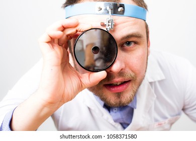 Doctor Otolaryngologist Close-up. On The Head Of The Doctor Is A Medical Reflector.