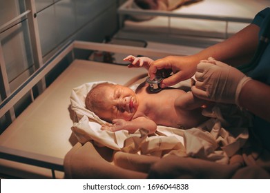 Doctor paediatrician examining baby in clinic, newborn baby crying in bed