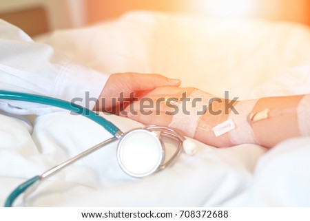 Doctor and patient concept. Hand of pediatrician physician holding illness child's hand connected with intravenous (IV) infusion treatment on hospital bed.