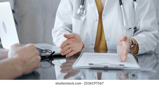 Doctor and patient consultation with clipboard and medication notes. Close-up view of unknown female doctor using a tablet during a patient consultation - Powered by Shutterstock