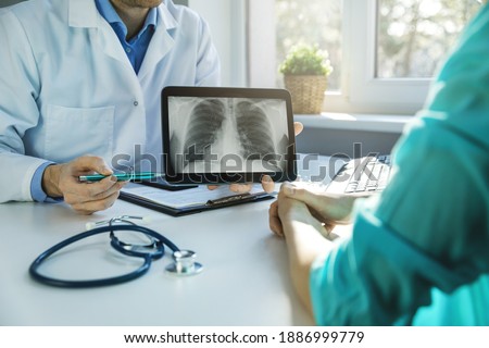 doctor and patient discuss chest x-ray results on digital tablet in clinics office