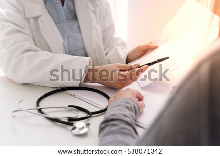 Doctor and patient are discussing about diagnosis, stethoscope and hands at the table.