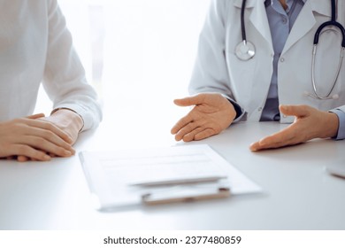 Doctor and patient discussing current health questions while sitting near of each other and using clipboard at the table in clinic, just hands closeup. Medicine concept - Shutterstock ID 2377480859