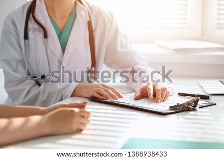 Doctor and patient are discussing something in clinic, just hands at the desk. Medicine and best service concept
