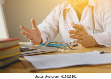 Doctor And Patient Are Discussing Something, Just Hands At The Table,explaining  Prescription To Victim,stethoscope And Laptop Computer On Desk In Hospital Healthcare And Medical Insurance Concept