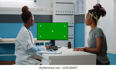 Doctor And Patient Looking At Computer With Horizontal Green Screen In Doctors Office. Medic And Woman Using Monitor With Chroma Key And Isolated Mockup Template And Background.