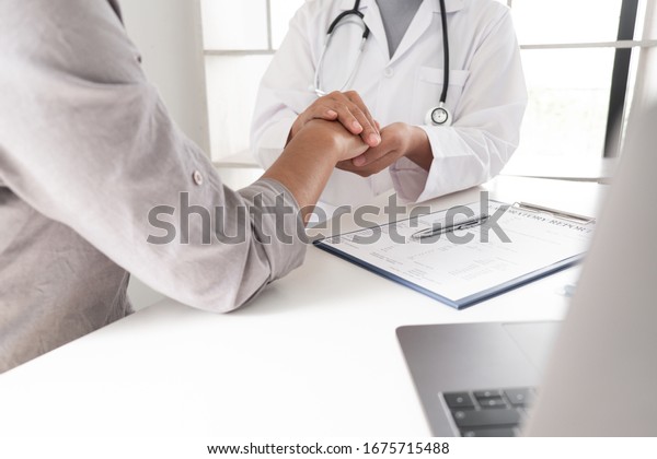 Doctor And A Patient Man Hand In Hand On The Table And Discussing